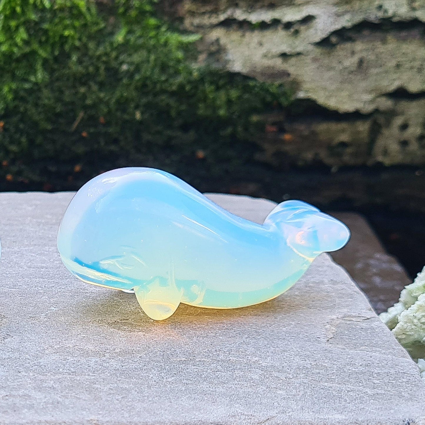 Opalite is a man-made stone that looks like glass. It has a beautiful opalescent appearance with a milky, blueish hue that shifts to a warm glow in certain lighting, resembling the natural iridescence of opal.