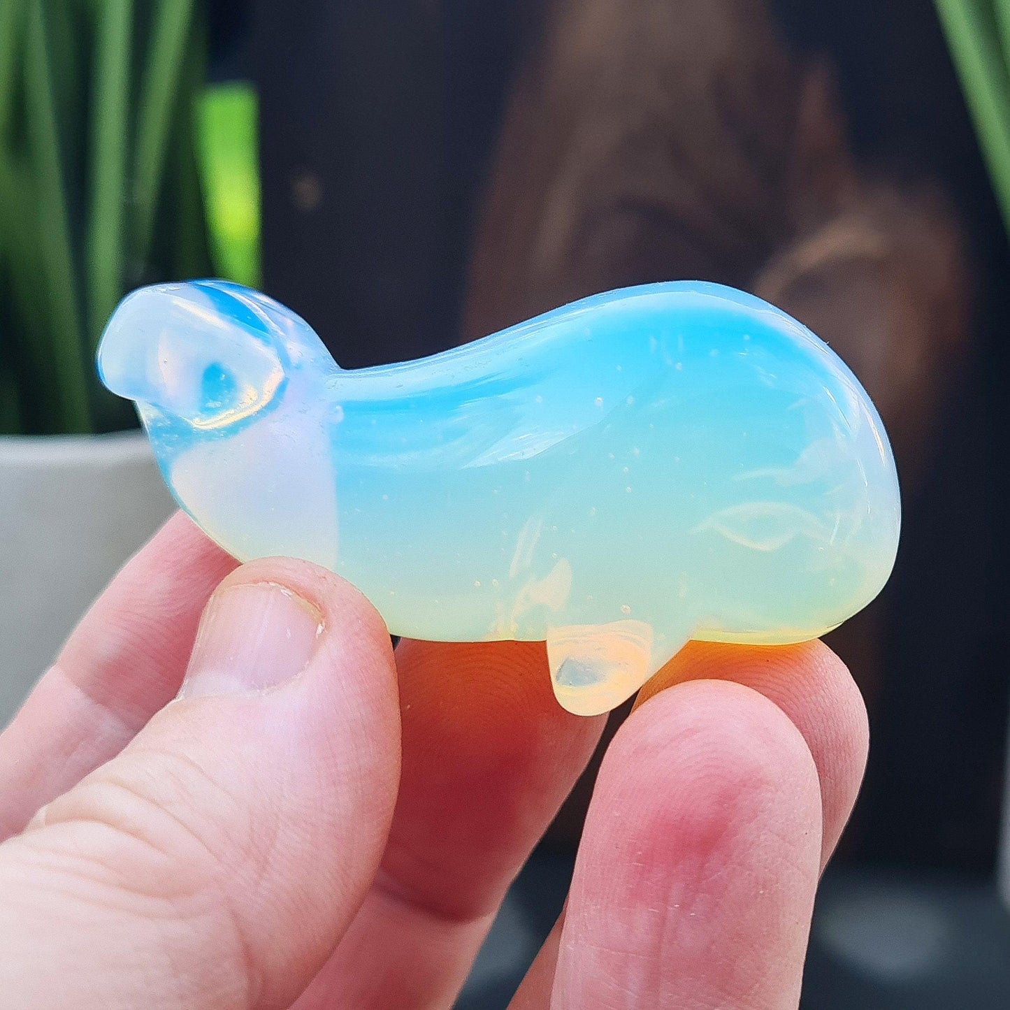 Opalite is a man-made stone that looks like glass. It has a beautiful opalescent appearance with a milky, blueish hue that shifts to a warm glow in certain lighting, resembling the natural iridescence of opal.