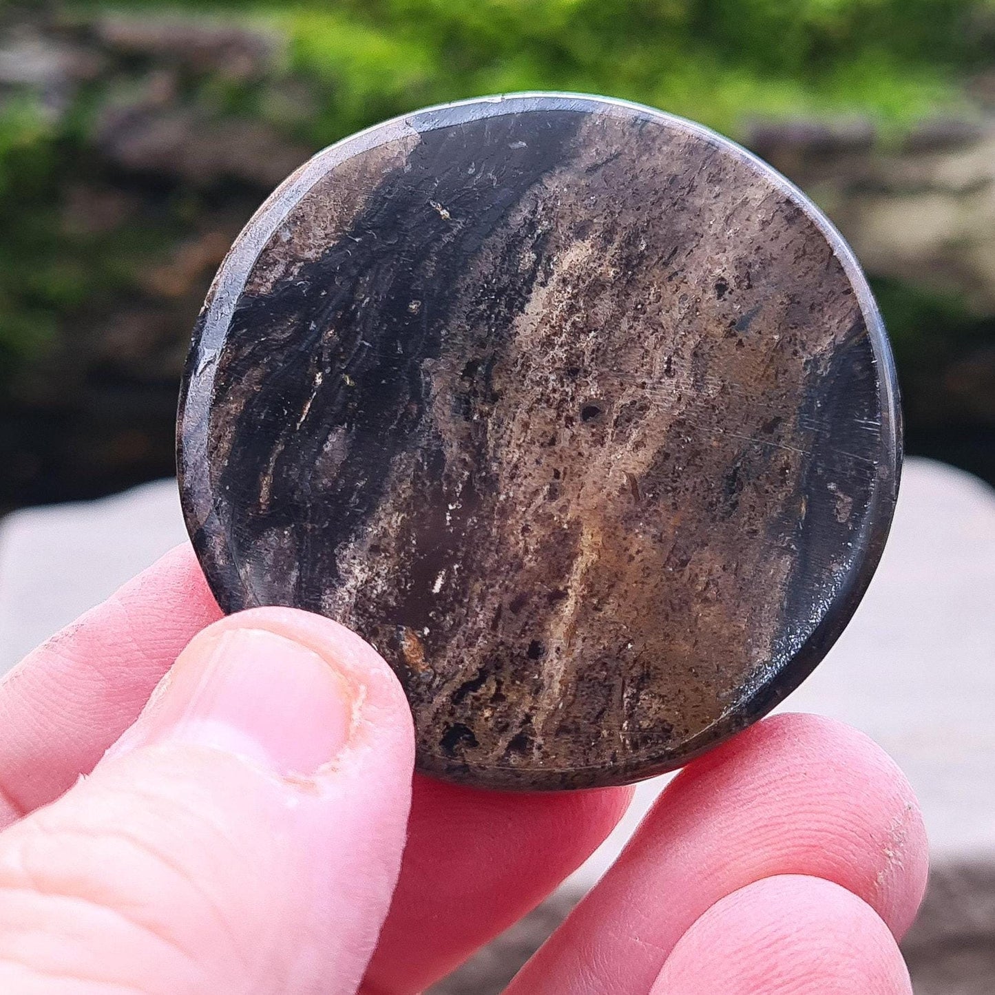 A beautifully polished disk of Obsidian, featuring deep brown and black tones. Smooth and tactile, this piece is perfect for holding during meditation or energy work. Its grounding energy makes it a powerful tool for emotional healing and protection.
