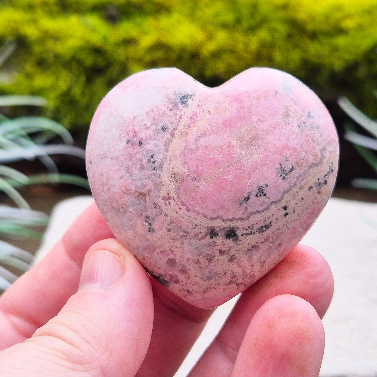 Pink Rhodonite Crystal Heart – also known as Bubblegum Pink Rhodonite from Peru. This beautiful heart-shaped Rhodonite crystal, sometimes nicknamed Bubblegum Pink Rhodonite, comes from Peru and features a soft pink colour with black patches caused by the natural oxidation of manganese.