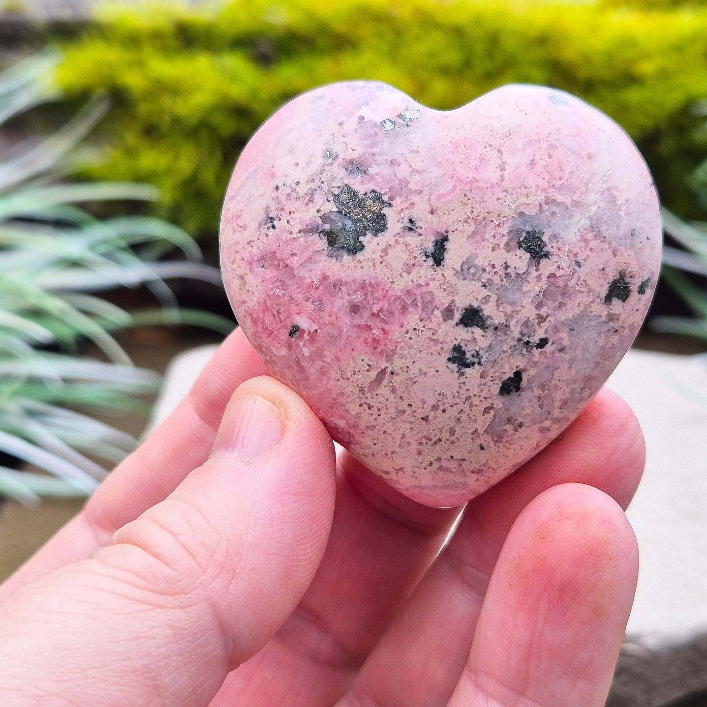 Pink Rhodonite Crystal Heart – also known as Bubblegum Pink Rhodonite from Peru. This beautiful heart-shaped Rhodonite crystal, sometimes nicknamed Bubblegum Pink Rhodonite, comes from Peru and features a soft pink colour with black patches caused by the natural oxidation of manganese.