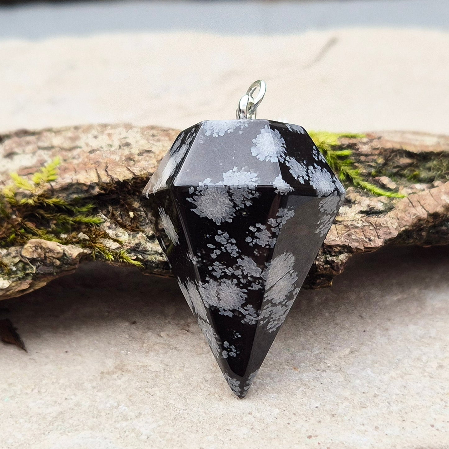 Snowflake Obsidian Crystal Pendulum from the USA. Comes in a organza pouch to keep it in. Chain has a metal ring at the end of it.