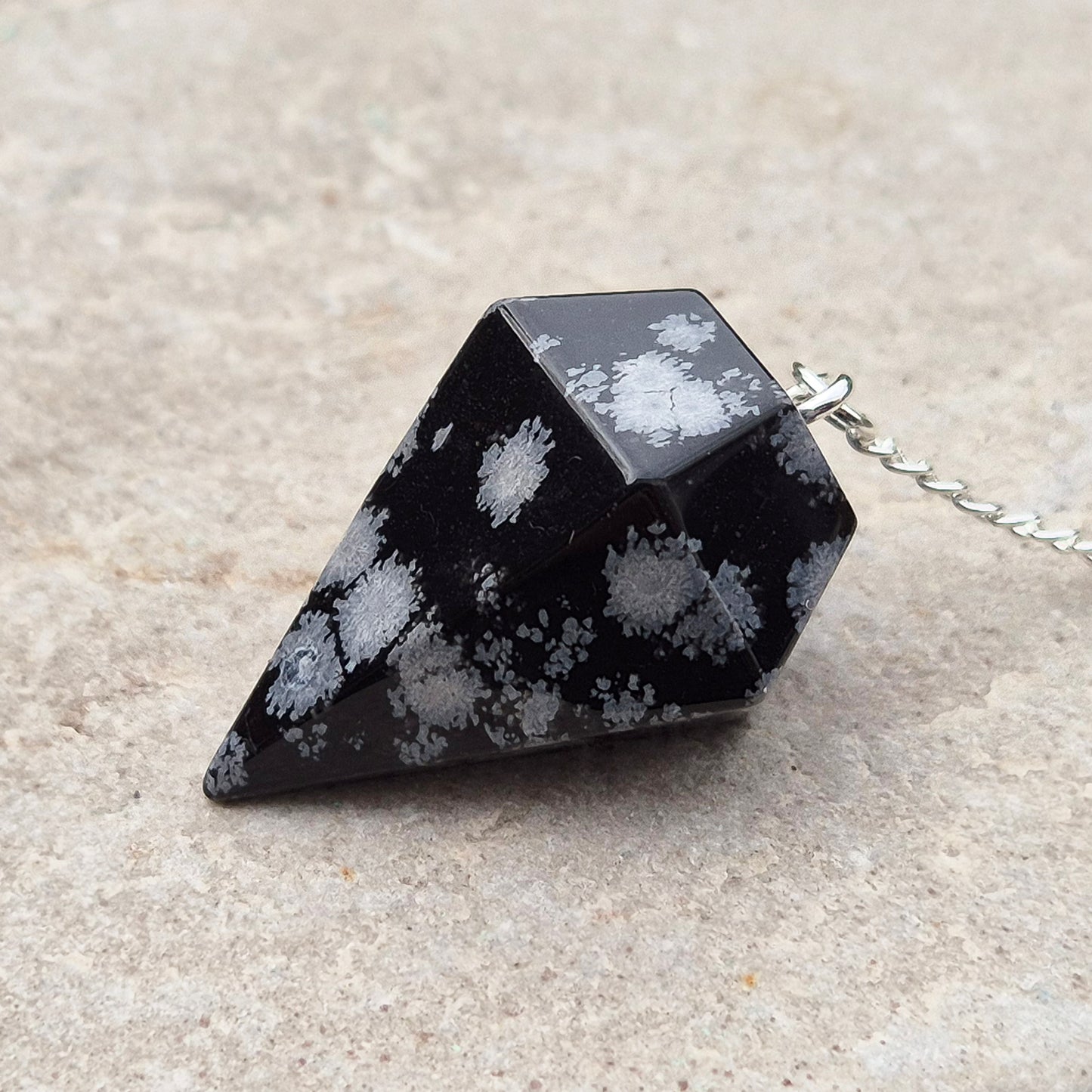 Snowflake Obsidian Crystal Pendulum from the USA. Comes in a organza pouch to keep it in. Chain has a metal ring at the end of it.