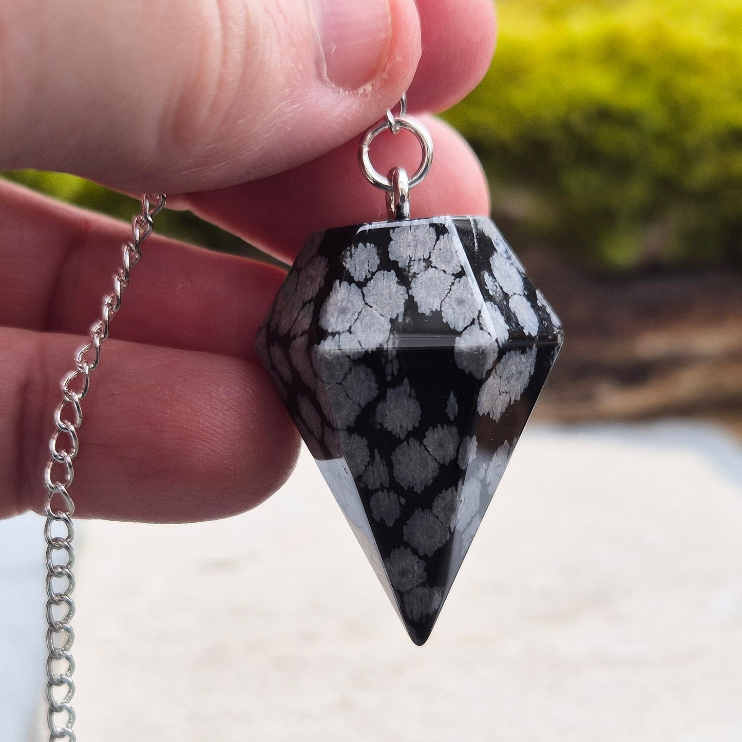 Snowflake Obsidian Crystal Pendulum from the USA. Comes in a organza pouch to keep it in. Chain has a metal ring at the end of it.