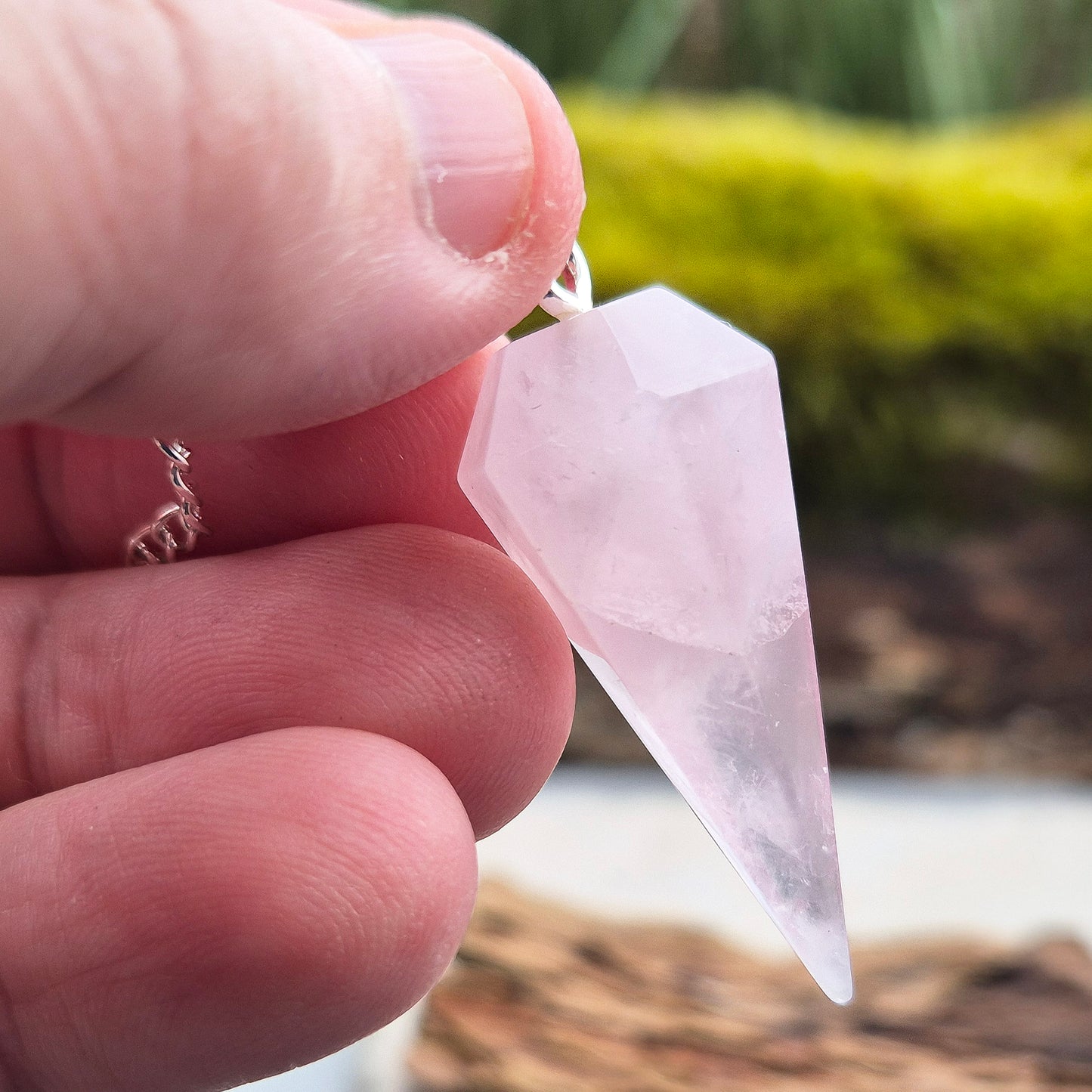 Rose Quartz Crystal Pendulum. comprises of a rose quartz crystal pendulum and a silver ring at the end of the chain.