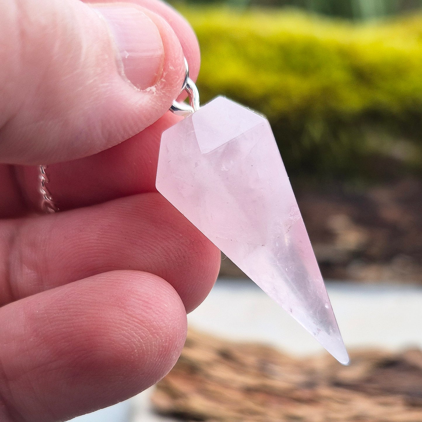 Rose Quartz Crystal Pendulum. comprises of a rose quartz crystal pendulum and a silver ring at the end of the chain.