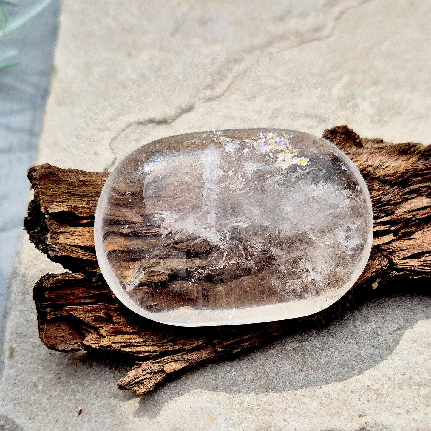 This beautifully polished Clear Quartz palm stone fits comfortably in the hand. Has light reflecting inclusions within it which catch the light.