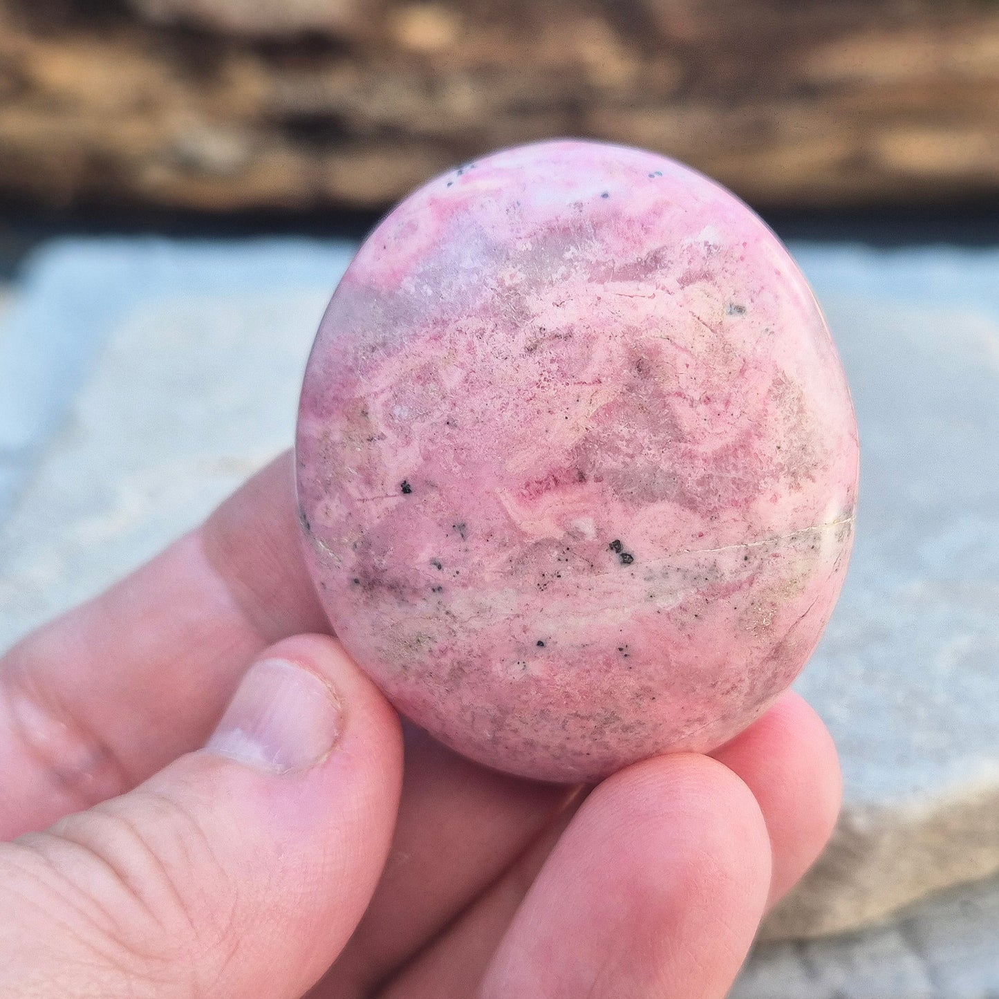 Pink Rhodonite Crystal Palm Stone – Also known as Bubblegum Pink Rhodonite from Peru. This soft pink Rhodonite, featuring natural black patches from manganese oxidation, is prized for its steady, reassuring energy.
