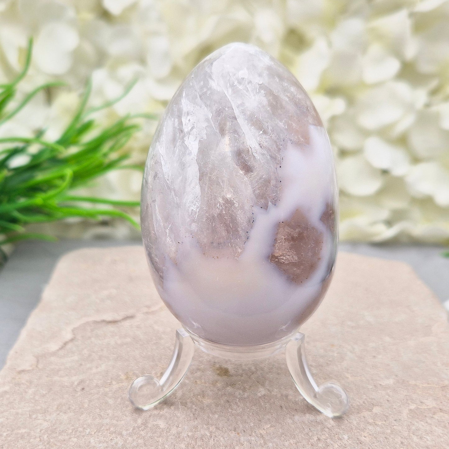 This beautiful Druzy Agate egg from Brazil is polished and showcases a sparkling pocket of natural druzy crystals in the middle of it. It comes with a clear acrylic stand, making it a lovely addition to any space or crystal shelf.