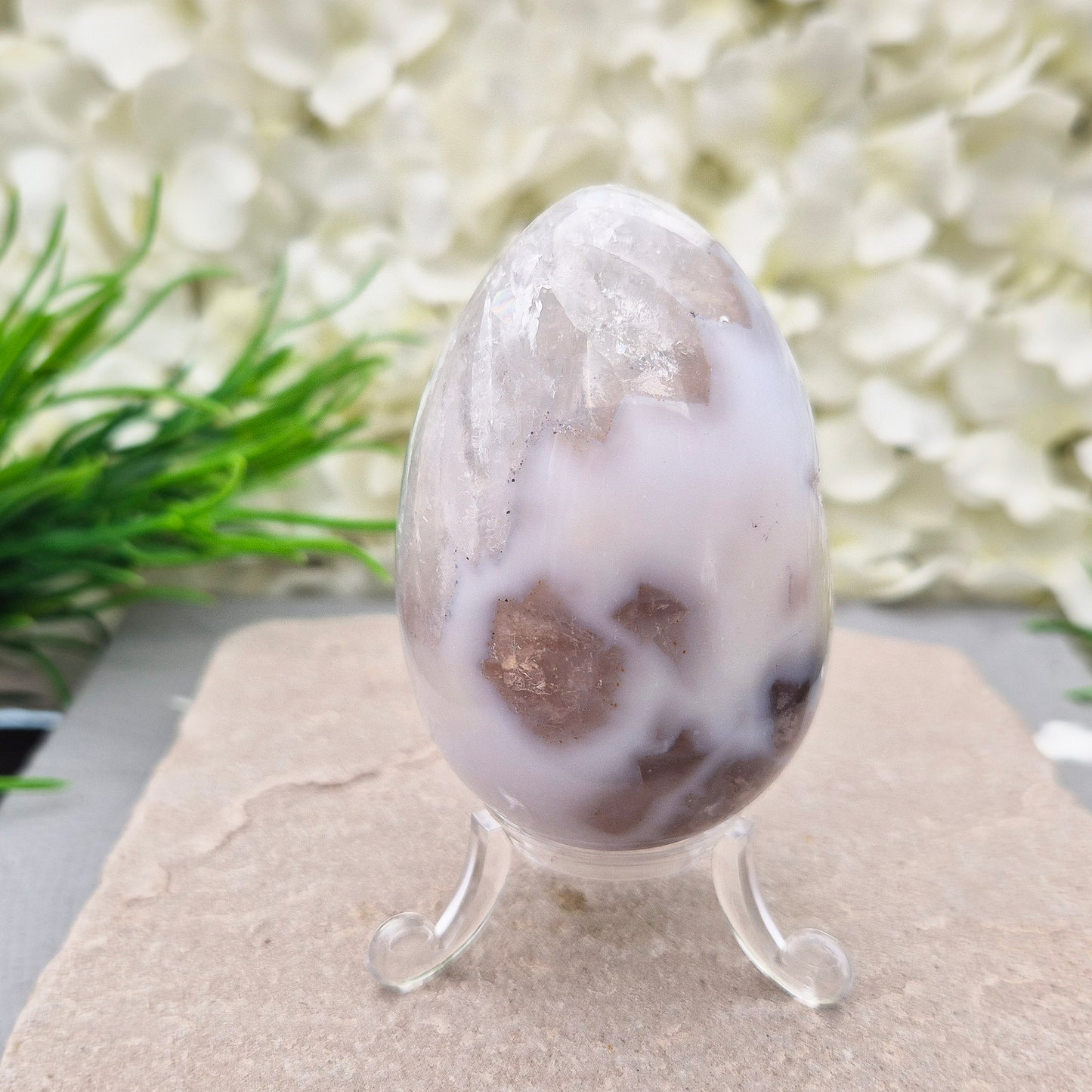 This beautiful Druzy Agate egg from Brazil is polished and showcases a sparkling pocket of natural druzy crystals in the middle of it. It comes with a clear acrylic stand, making it a lovely addition to any space or crystal shelf.