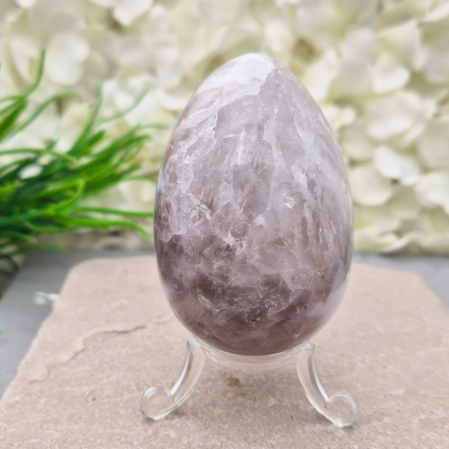 This beautiful Druzy Agate egg from Brazil is polished and showcases a sparkling pocket of natural druzy crystals in the middle of it. It comes with a clear acrylic stand, making it a lovely addition to any space or crystal shelf.