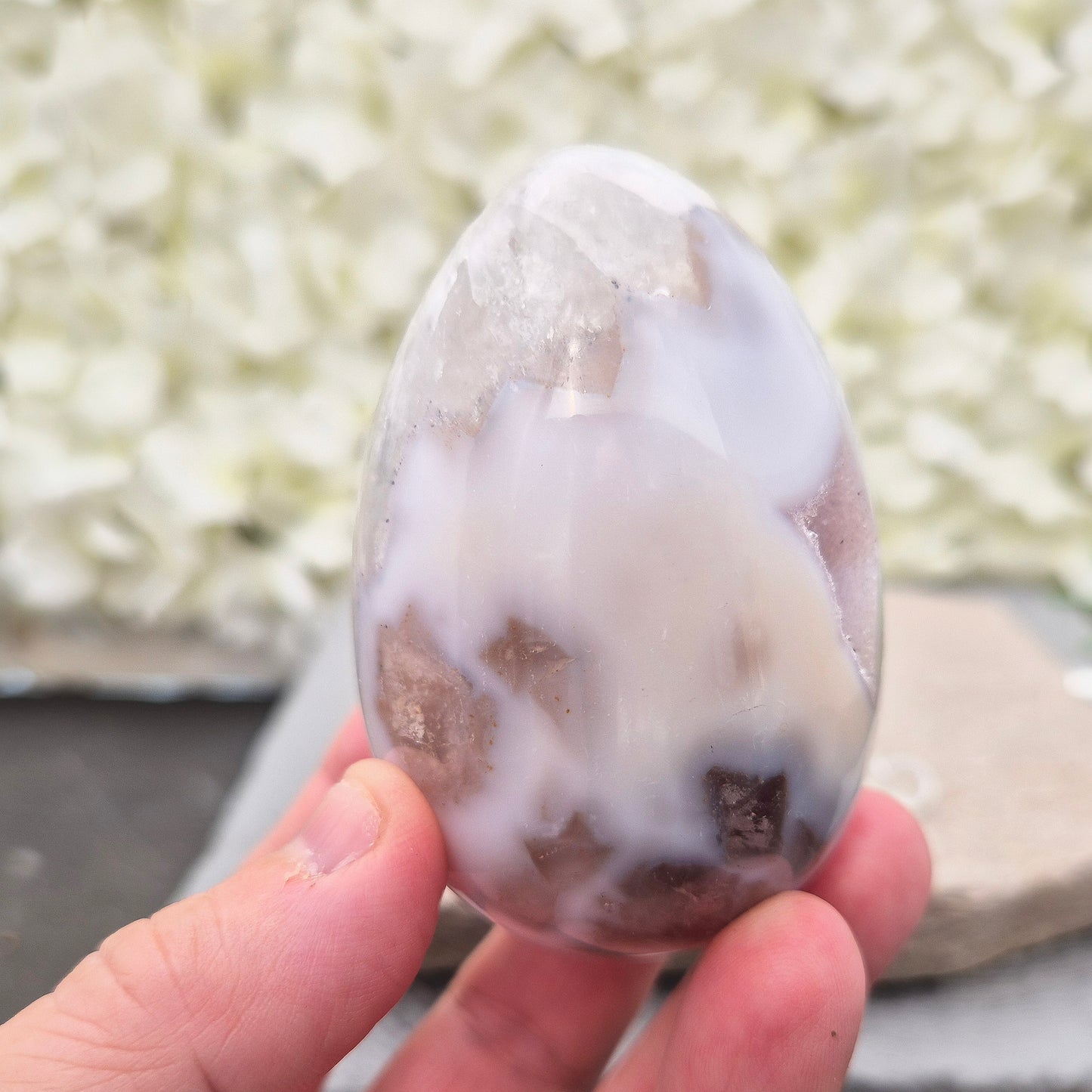 This beautiful Druzy Agate egg from Brazil is polished and showcases a sparkling pocket of natural druzy crystals in the middle of it. It comes with a clear acrylic stand, making it a lovely addition to any space or crystal shelf.