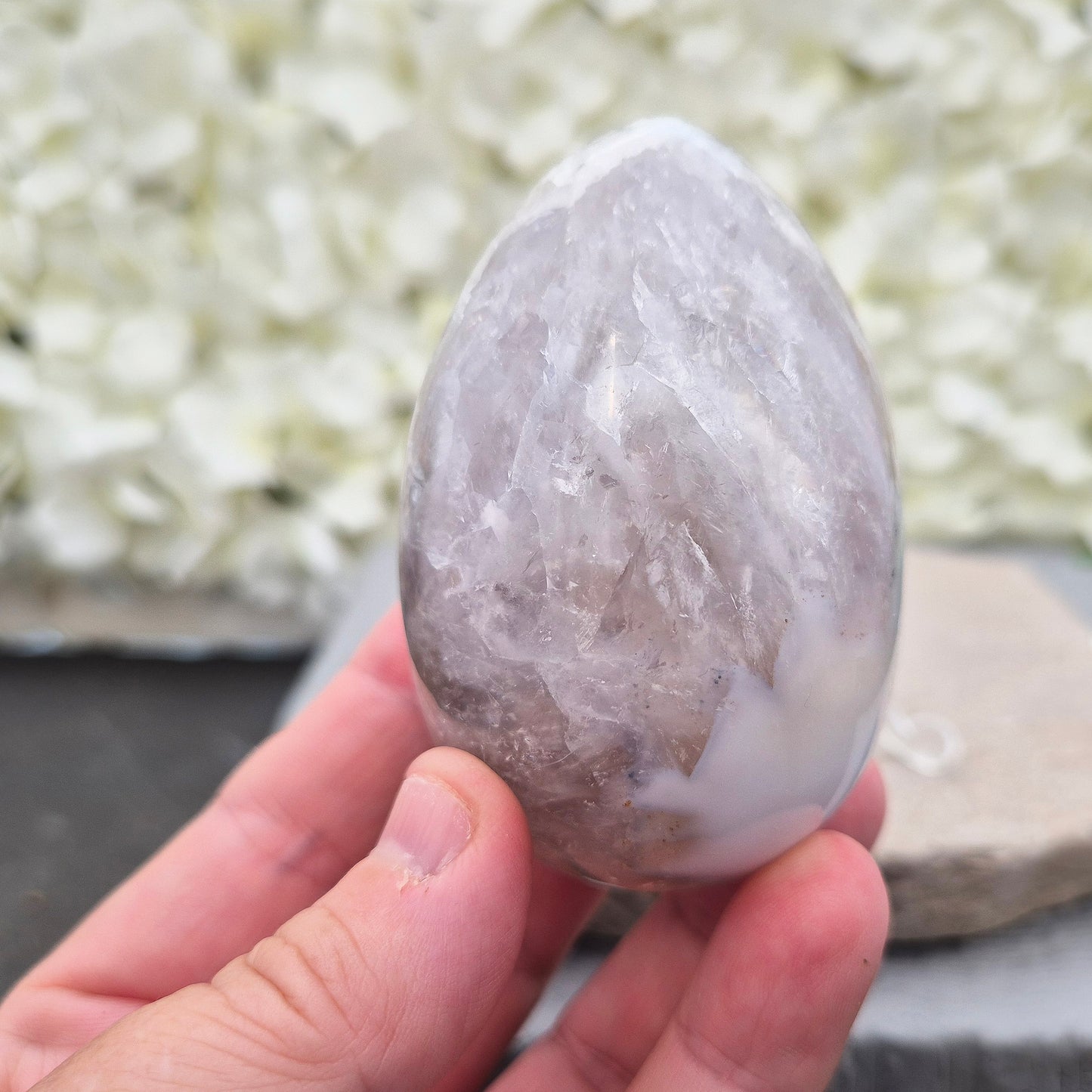 This beautiful Druzy Agate egg from Brazil is polished and showcases a sparkling pocket of natural druzy crystals in the middle of it. It comes with a clear acrylic stand, making it a lovely addition to any space or crystal shelf.