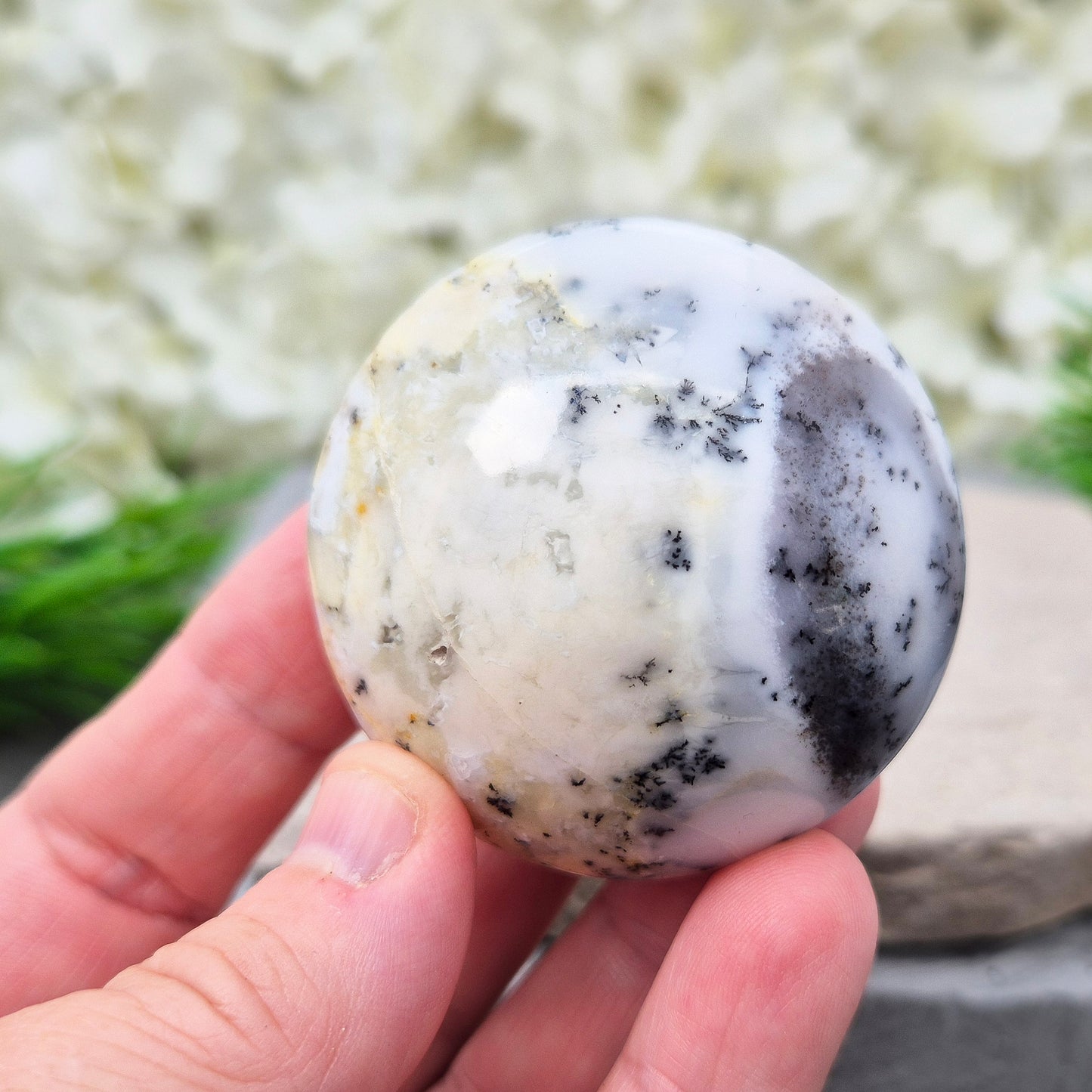This stunning Merlinite galet from Madagascar features soft off-white and grey colouring with black dendritic (fern-like) inclusions of Psilomelane. Its polished, circular shape makes it a perfect tactile piece for meditation and spiritual work.