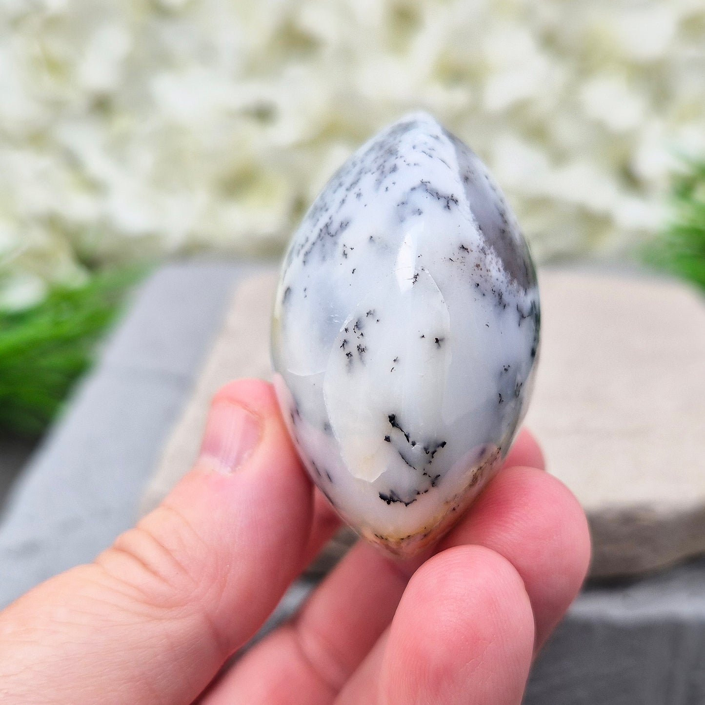 This stunning Merlinite galet from Madagascar features soft off-white and grey colouring with black dendritic (fern-like) inclusions of Psilomelane. Its polished, circular shape makes it a perfect tactile piece for meditation and spiritual work.