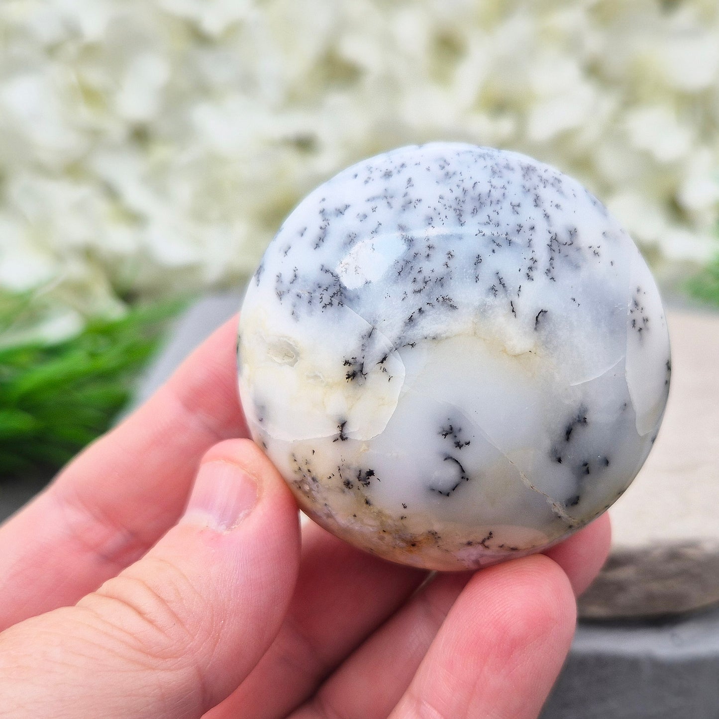 This stunning Merlinite galet from Madagascar features soft off-white and grey colouring with black dendritic (fern-like) inclusions of Psilomelane. Its polished, circular shape makes it a perfect tactile piece for meditation and spiritual work.