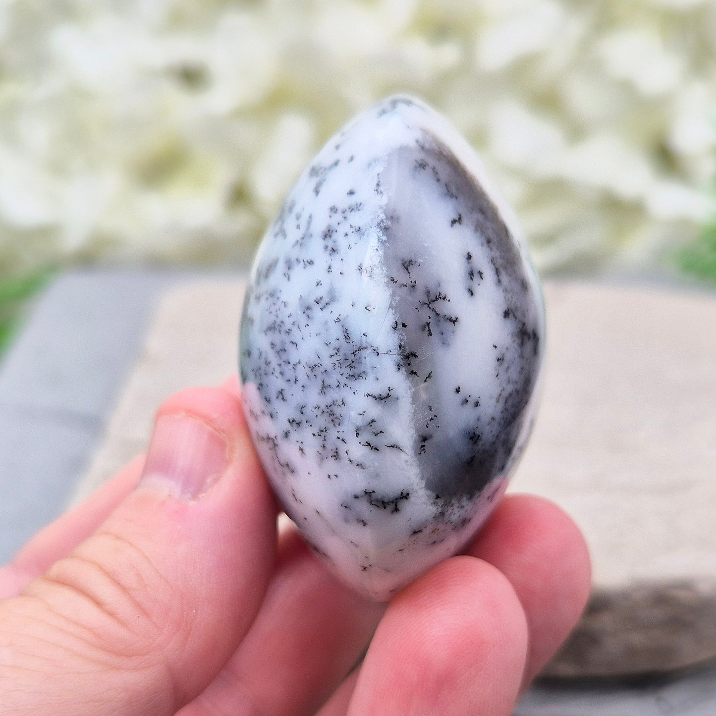 This stunning Merlinite galet from Madagascar features soft off-white and grey colouring with black dendritic (fern-like) inclusions of Psilomelane. Its polished, circular shape makes it a perfect tactile piece for meditation and spiritual work.