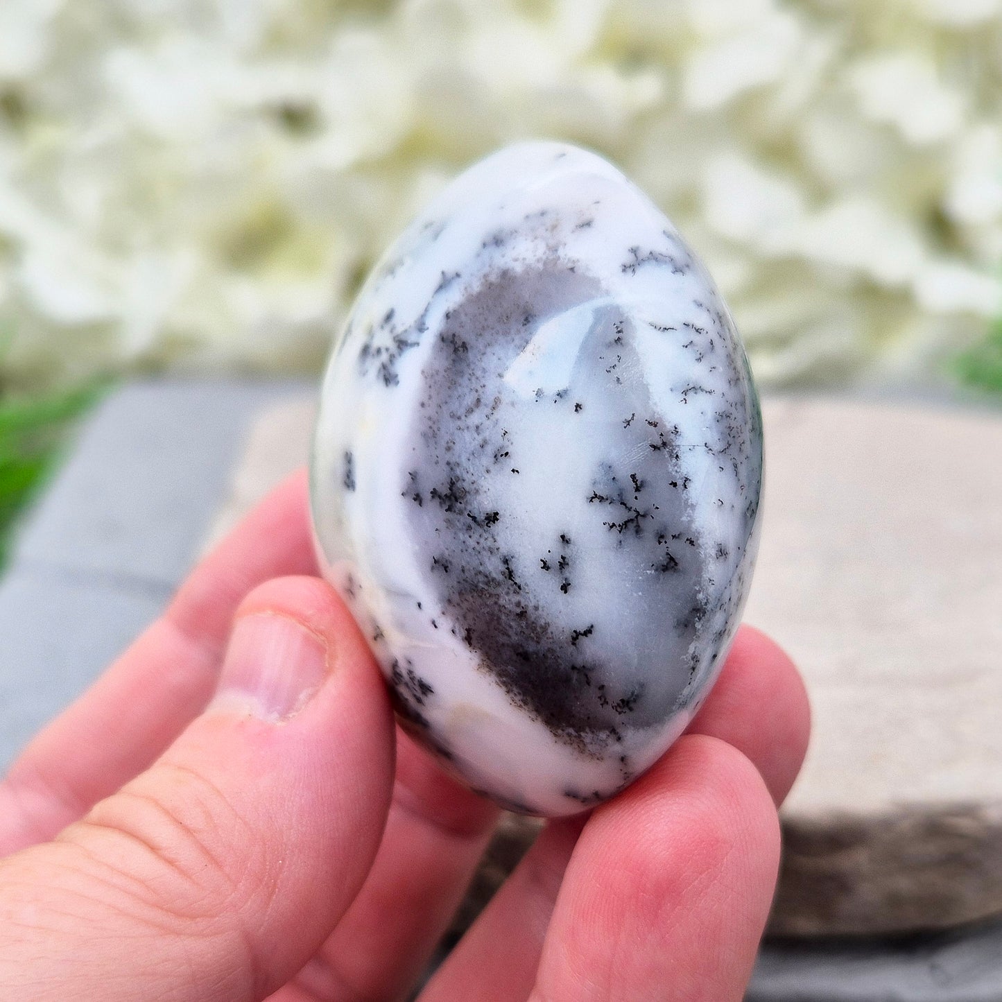 This stunning Merlinite galet from Madagascar features soft off-white and grey colouring with black dendritic (fern-like) inclusions of Psilomelane. Its polished, circular shape makes it a perfect tactile piece for meditation and spiritual work.