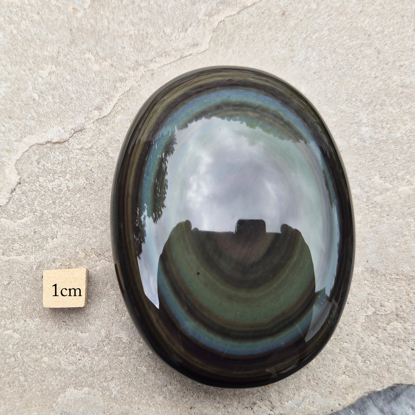 This highly polished, generously sized Rainbow Obsidian palmstone from Mexico reveals bands of deep green, gold, and shadowy blue — colours that only appear when the light hits just right.
