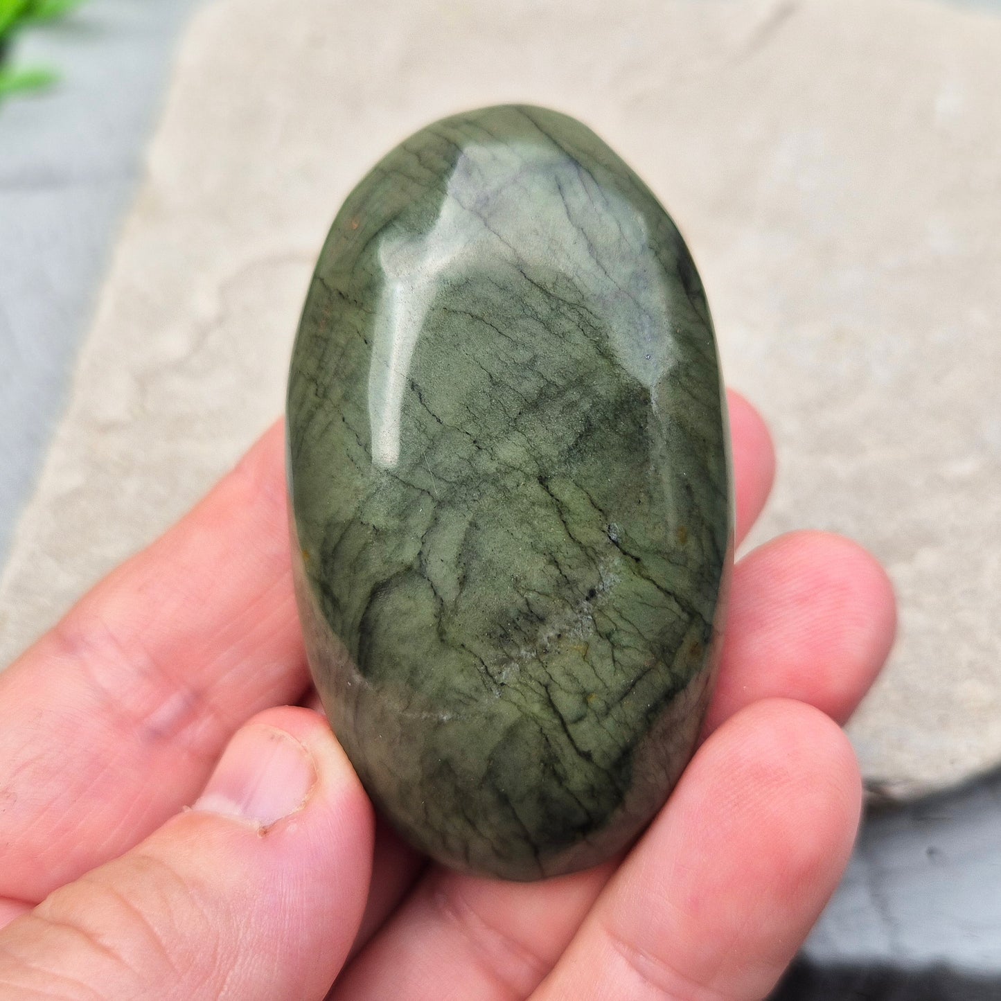 This smooth, polished Nephrite Jade palm stone from Pakistan features classic deep green tones. Nephrite Jade has long been seen as a stone of luck and wellbeing — but it's also a true ally for emotional balance and inner strength.