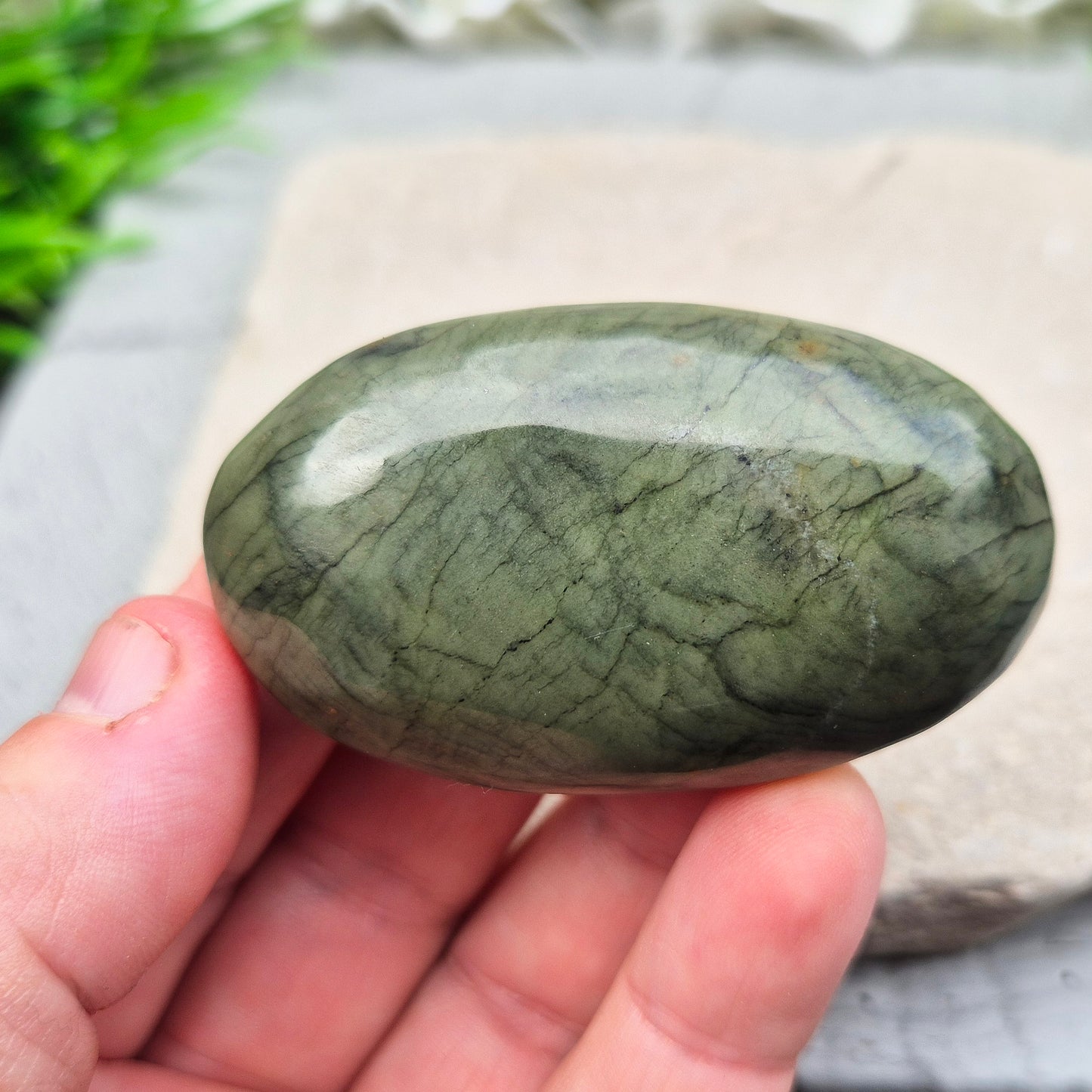 This smooth, polished Nephrite Jade palm stone from Pakistan features classic deep green tones. Nephrite Jade has long been seen as a stone of luck and wellbeing — but it's also a true ally for emotional balance and inner strength. T