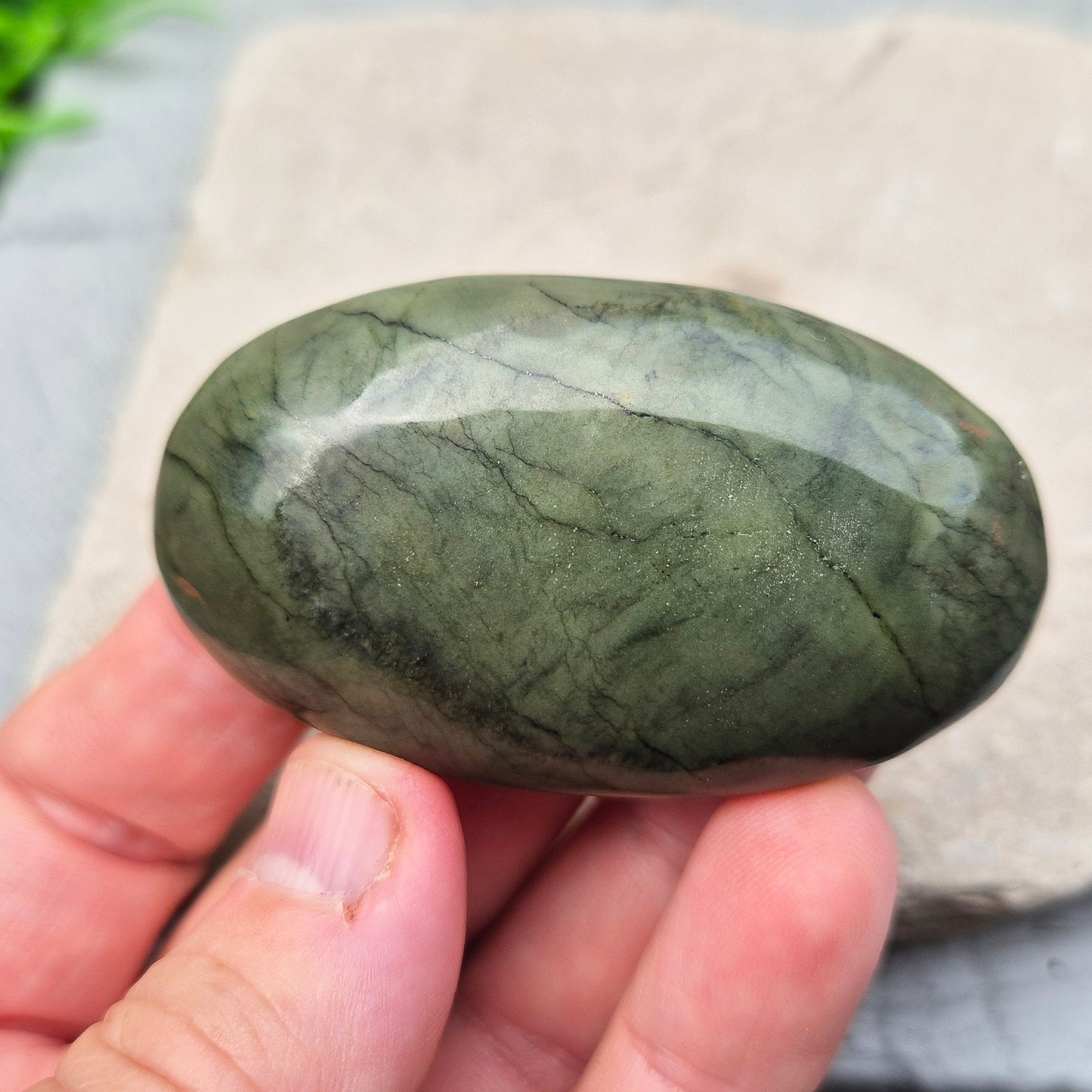 This smooth, polished Nephrite Jade palm stone from Pakistan features classic deep green tones. Nephrite Jade has long been seen as a stone of luck and wellbeing — but it's also a true ally for emotional balance and inner strength.