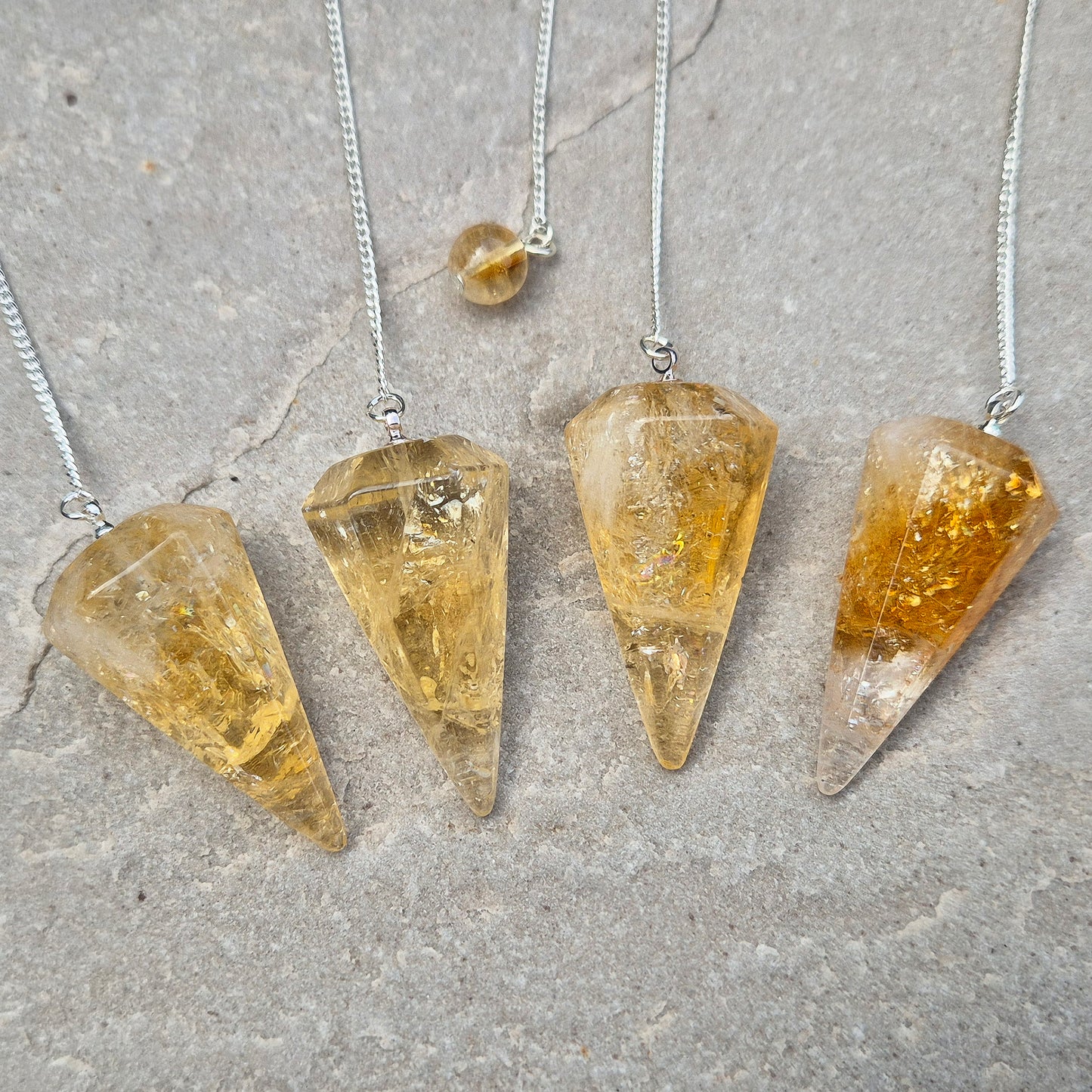 Citrine Crystal Pendulum from Brazil. These stunning sunny pendulums carry the warm, golden glow Citrine is loved for. Each has a yellow bead at the end of the chain making it comfortable to hold and easy to use.