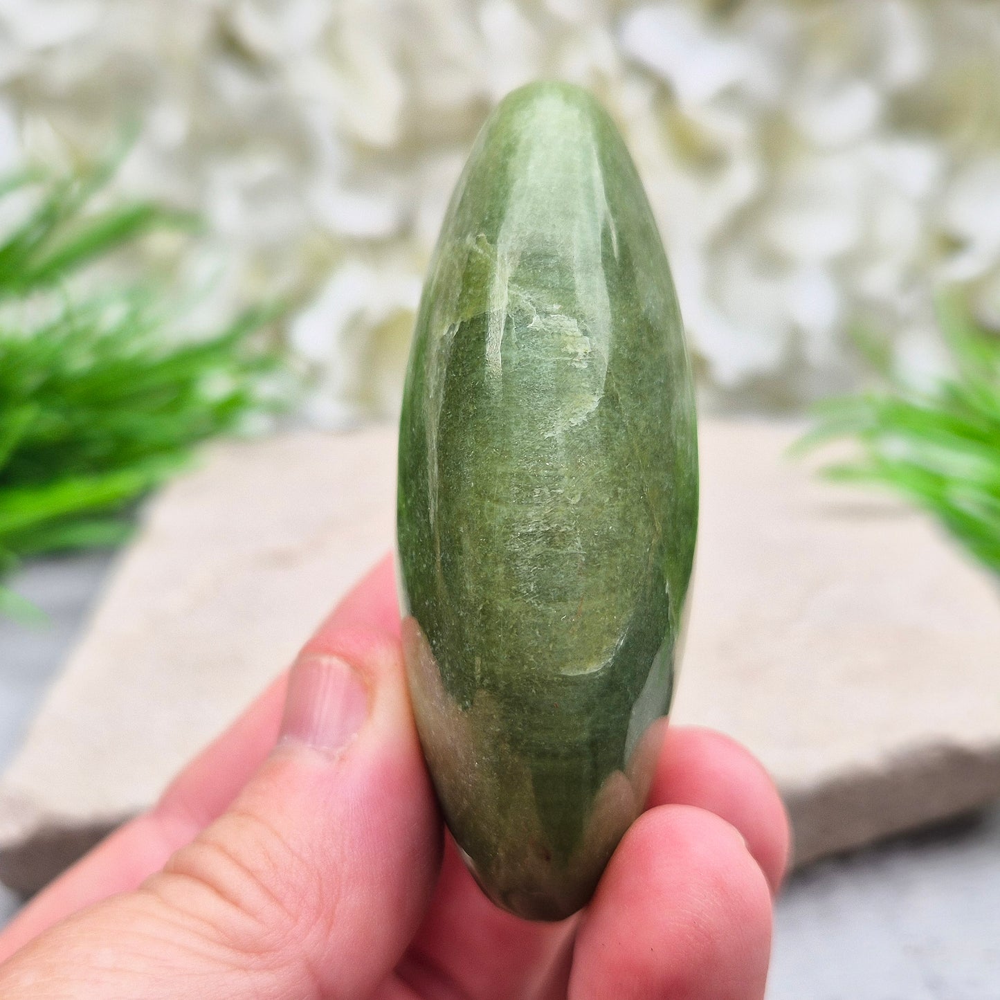 This lovely Tremolite palm stone from the United States shows soft green colouring with a smooth, polished finish. Tremolite forms when rocks such as limestone undergo heat and pressure, creating a crystal that appears in shades of white, grey, green, or light brown.