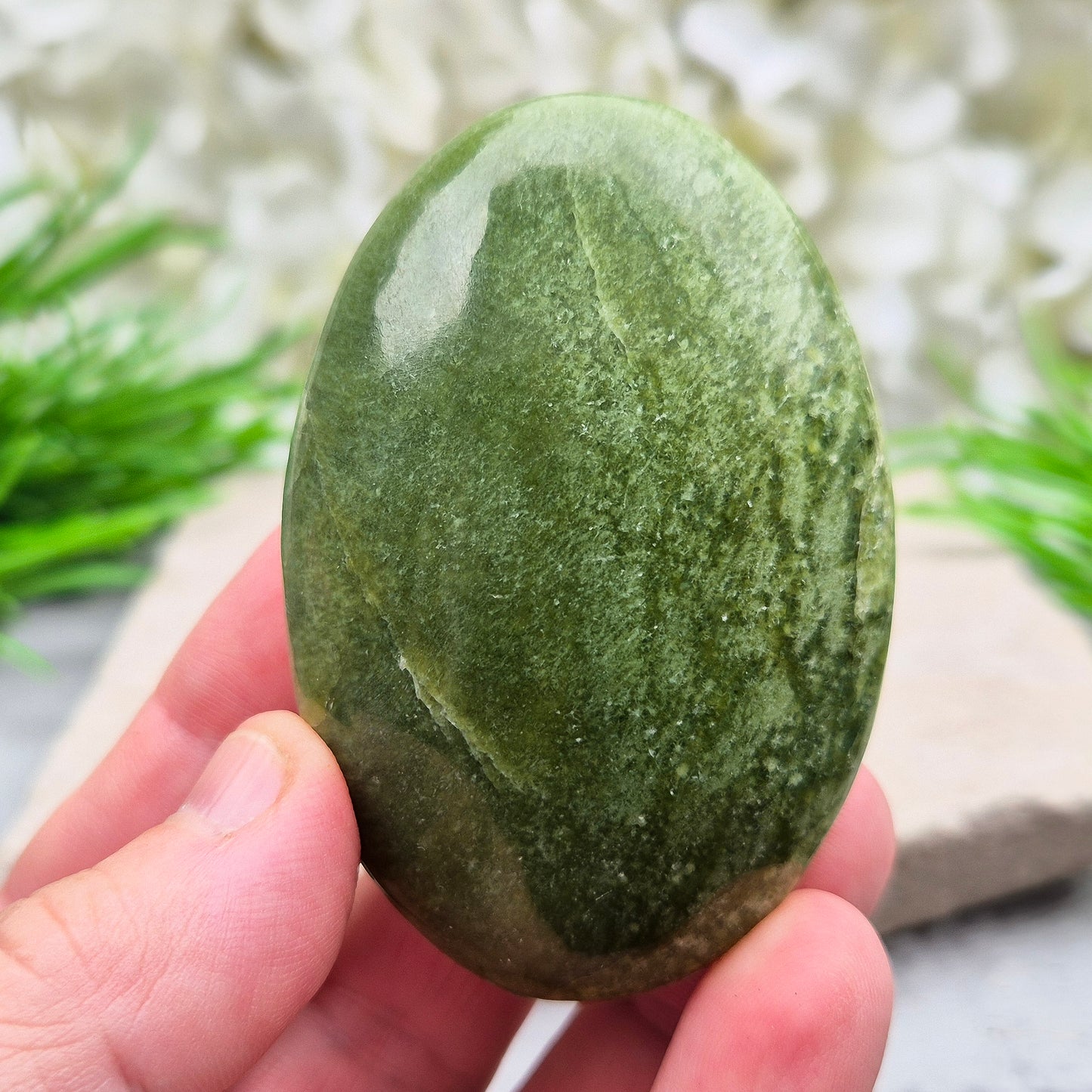 This lovely Tremolite palm stone from the United States shows soft green colouring with a smooth, polished finish. Tremolite forms when rocks such as limestone undergo heat and pressure, creating a crystal that appears in shades of white, grey, green, or light brown.