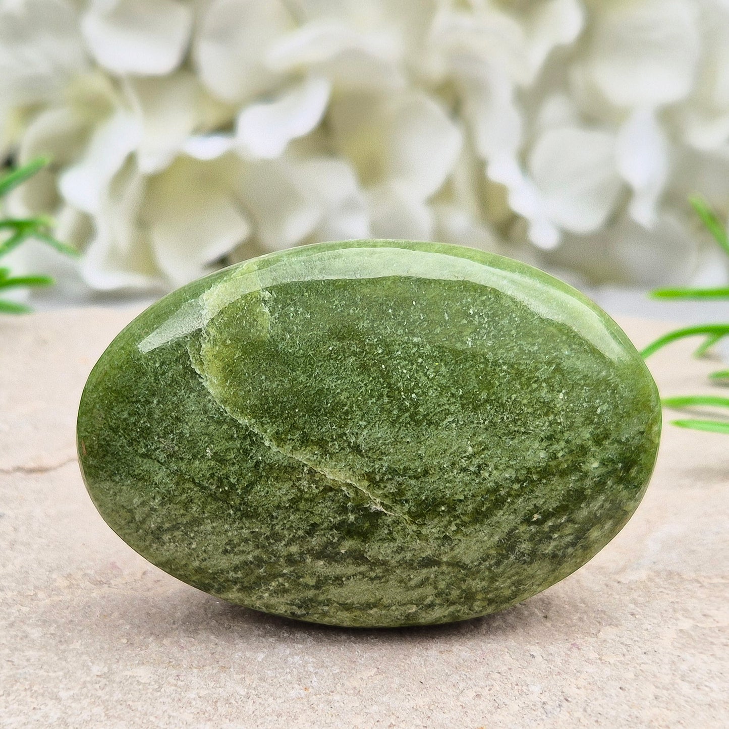 This lovely Tremolite palm stone from the United States shows soft green colouring with a smooth, polished finish. Tremolite forms when rocks such as limestone undergo heat and pressure, creating a crystal that appears in shades of white, grey, green, or light brown.
