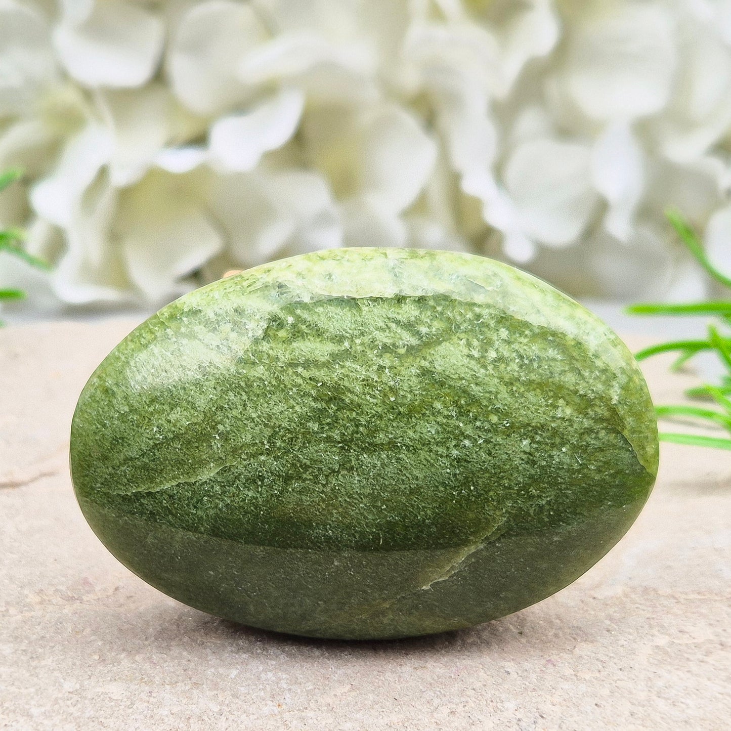 This lovely Tremolite palm stone from the United States shows soft green colouring with a smooth, polished finish. Tremolite forms when rocks such as limestone undergo heat and pressure, creating a crystal that appears in shades of white, grey, green, or light brown.