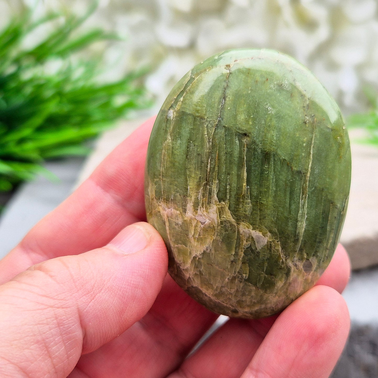 This lovely Tremolite palm stone from the United States shows soft green colouring with a smooth, polished finish. Tremolite forms when rocks such as limestone undergo heat and pressure, creating a crystal that appears in shades of white, grey, green, or light brown.