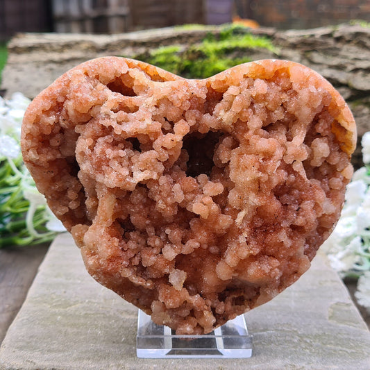 This striking Red Amethyst Heart showcases natural druzy crystal formations in shades of dusky pink/red. Its polished sides and natural base allow it to sit flat, while the included stand lets you display it upright as a beautiful statement piece.