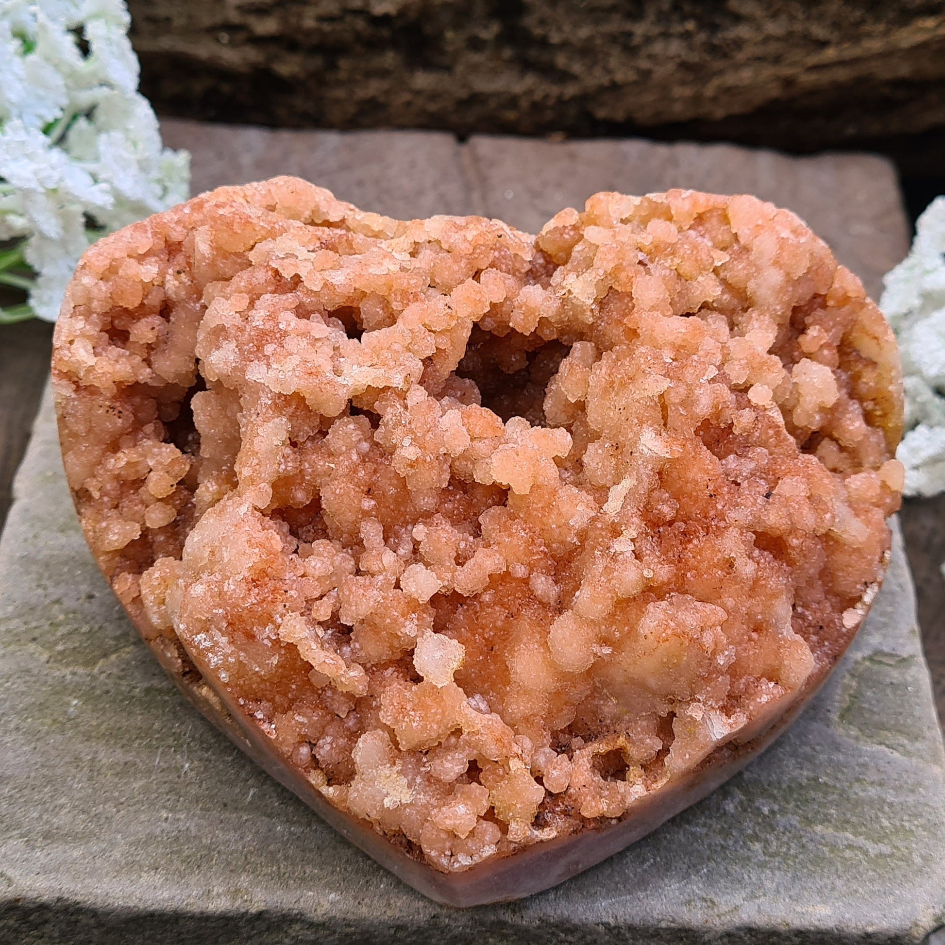 This striking Red Amethyst Heart showcases natural druzy crystal formations in shades of dusky pink/red. Its polished sides and natural base allow it to sit flat, while the included stand lets you display it upright as a beautiful statement piece.