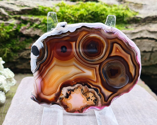 Agate Slice from Brazil, with stunning patterning and colouring. The edges have been left natural, the rest of the slice is polished. Stand not included. The pink colouring on this piece may not be naturally occurring.