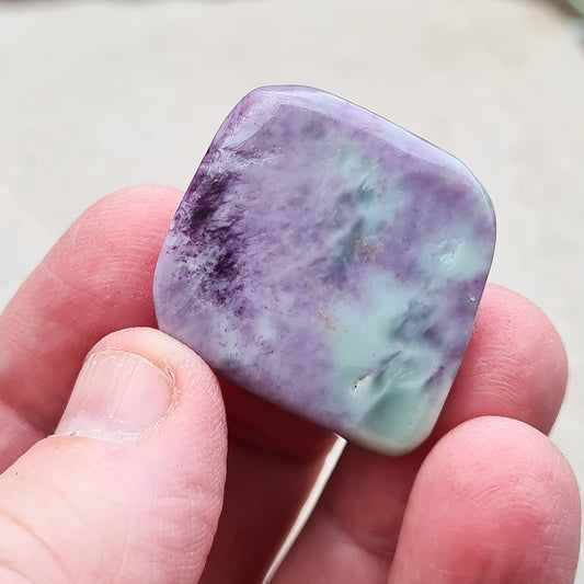 Tumbled, polished Kammererite. The Kammererite itself is a purple-magenta colour, and any green areas you see are normally the inclusion of Chromate, Chlorite or Serpentine.