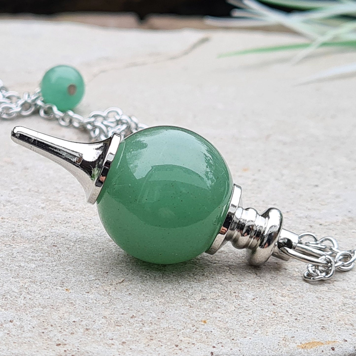 Green Aventurine Crystal Pendulum. comprises of a Green Aventurine crystal ball and metal tip pendulum fixing and a green bead at the end of the chain. Comes in a box or pouch.