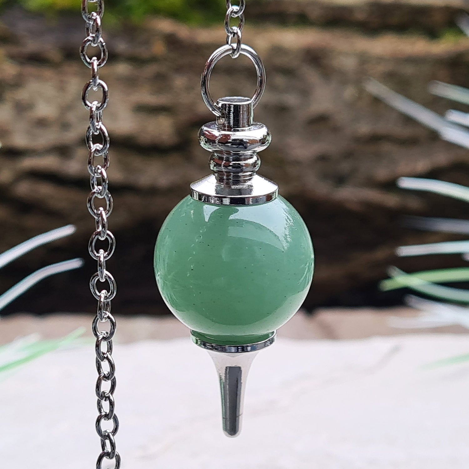 Green Aventurine Crystal Pendulum. comprises of a Green Aventurine crystal ball and metal tip pendulum fixing and a green bead at the end of the chain. Comes in a box or pouch.