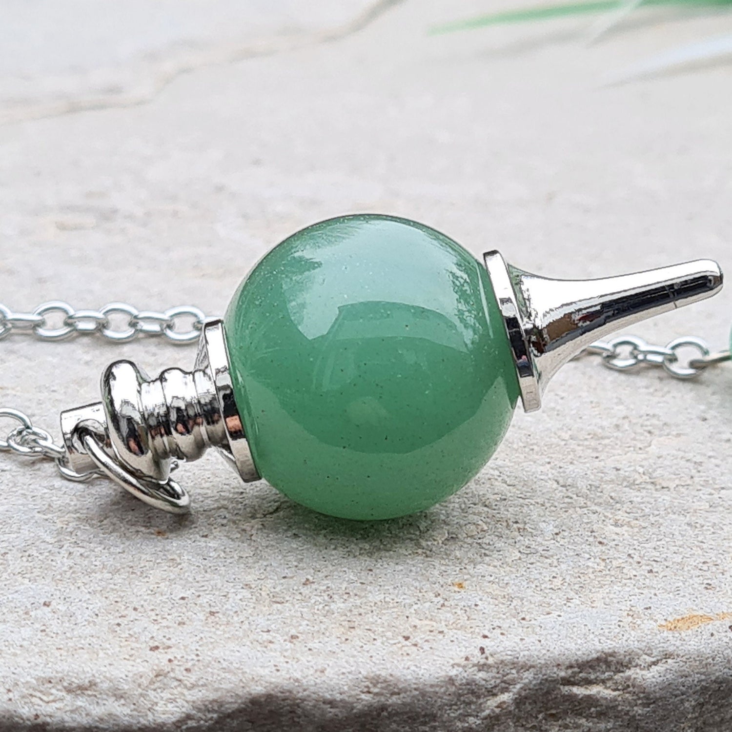 Green Aventurine Crystal Pendulum. comprises of a Green Aventurine crystal ball and metal tip pendulum fixing and a green bead at the end of the chain. Comes in a box or pouch.