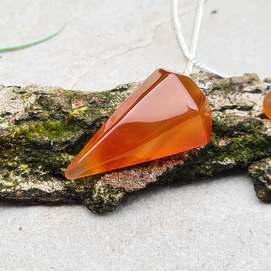 Carnelian Crystal Pendulum. From Madagascar. This pendulum has great orange colouring, and it has a druzy pocket towards the tip which is really unusual. The chain has an orange bead at the end. 