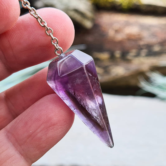 Dark Amethyst Crystal Pendulum. Lovely dark purple colour crystal, when held in the light you can see the smoky amethyst phantom inside. Chain has a purple bead on the end. 