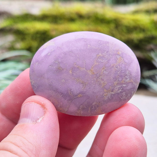 Phosphosiderite palm stone featuring soothing light purple hues, known for its emotional healing properties and ability to enhance spiritual awareness and inner peace.