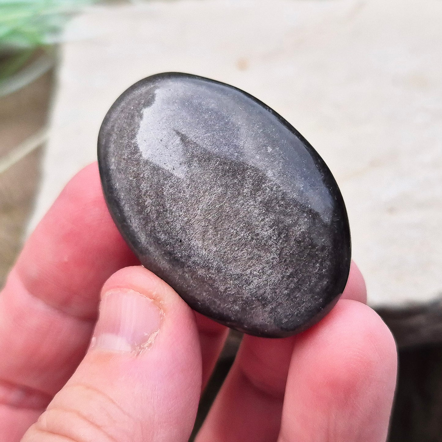 Silver Sheen Obsidian Crystal Palm Stone. Silver sheen obsidian is a type of volcanic glass which is primarily black or dark grey and has a distinctive silvery or metallic sheen on its surface