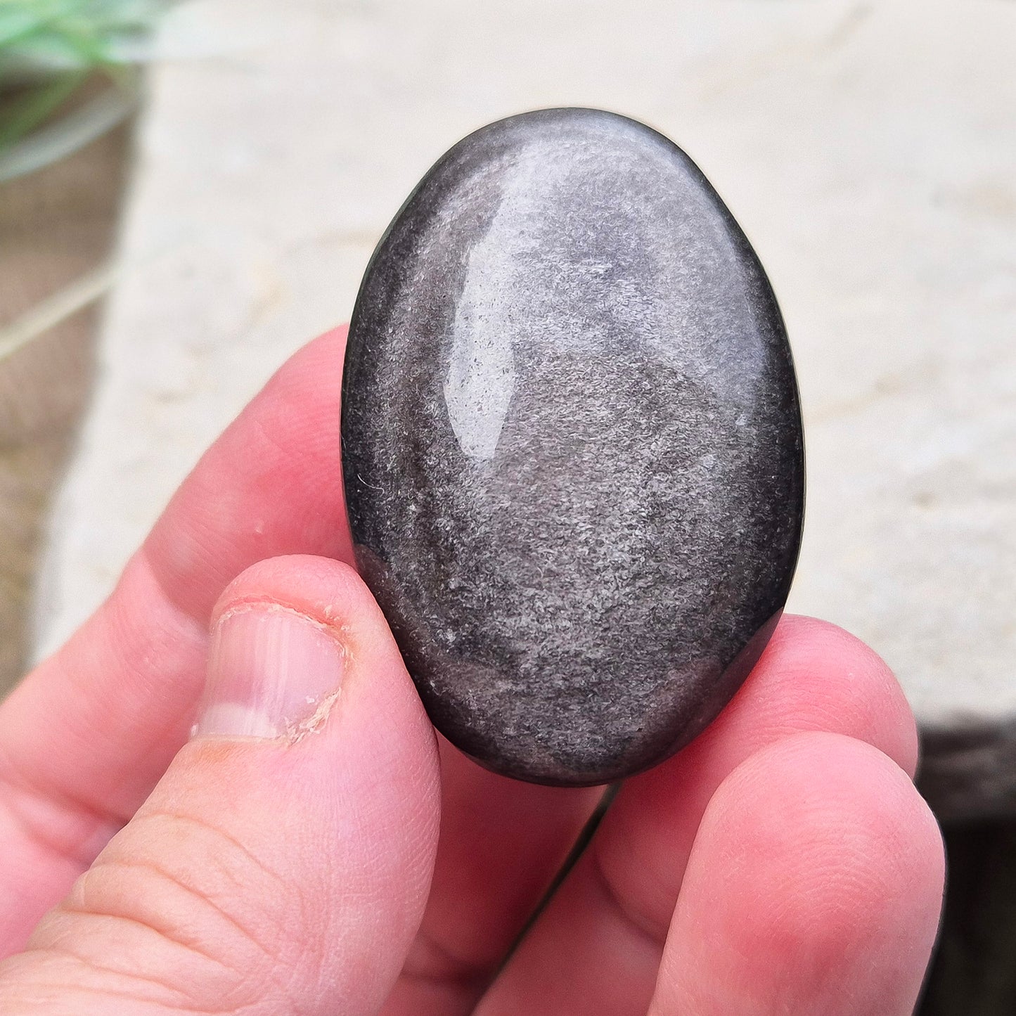 Silver Sheen Obsidian Crystal Palm Stone. Silver sheen obsidian is a type of volcanic glass which is primarily black or dark grey and has a distinctive silvery or metallic sheen on its surface