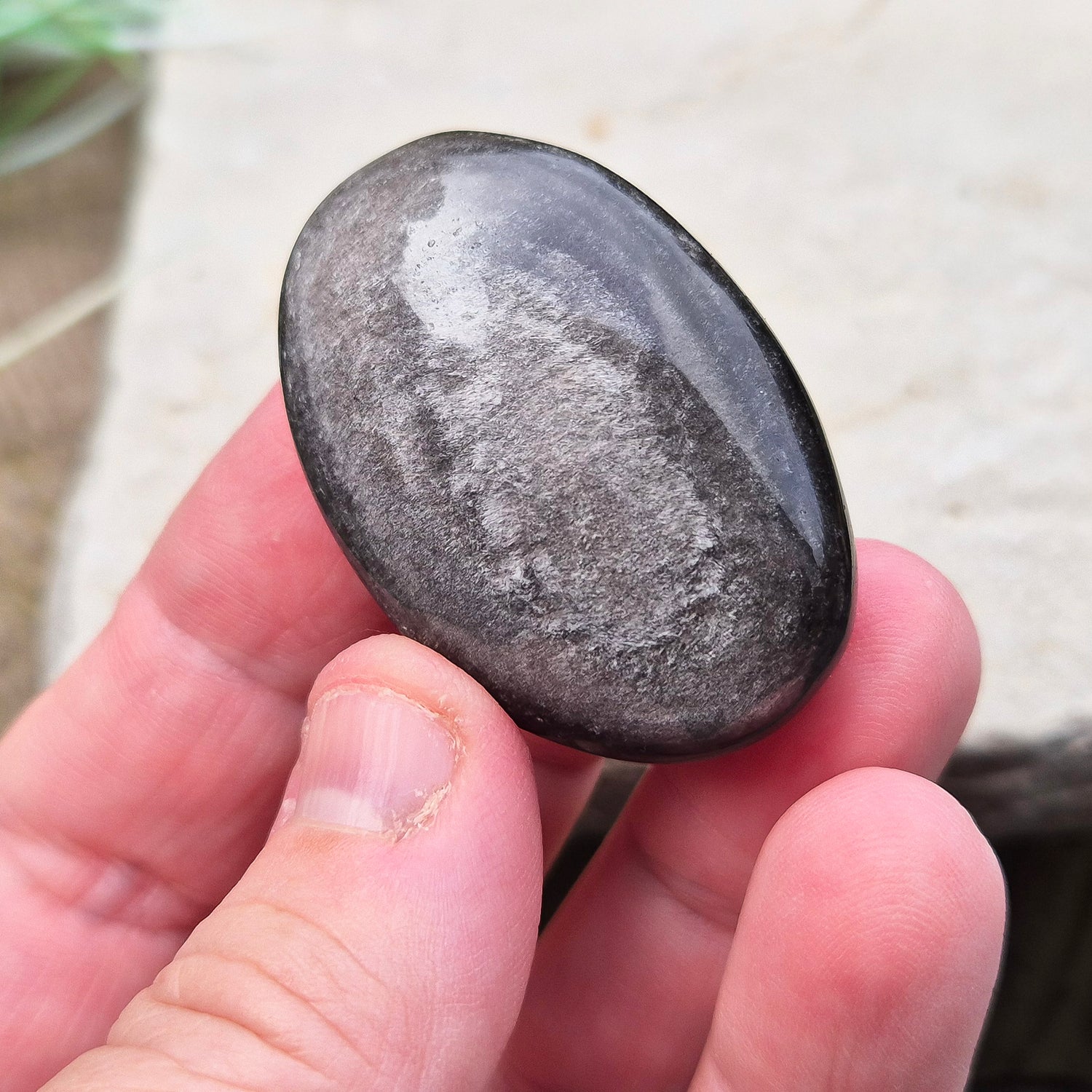 Silver Sheen Obsidian Crystal Palm Stone. Silver sheen obsidian is a type of volcanic glass which is primarily black or dark grey and has a distinctive silvery or metallic sheen on its surface