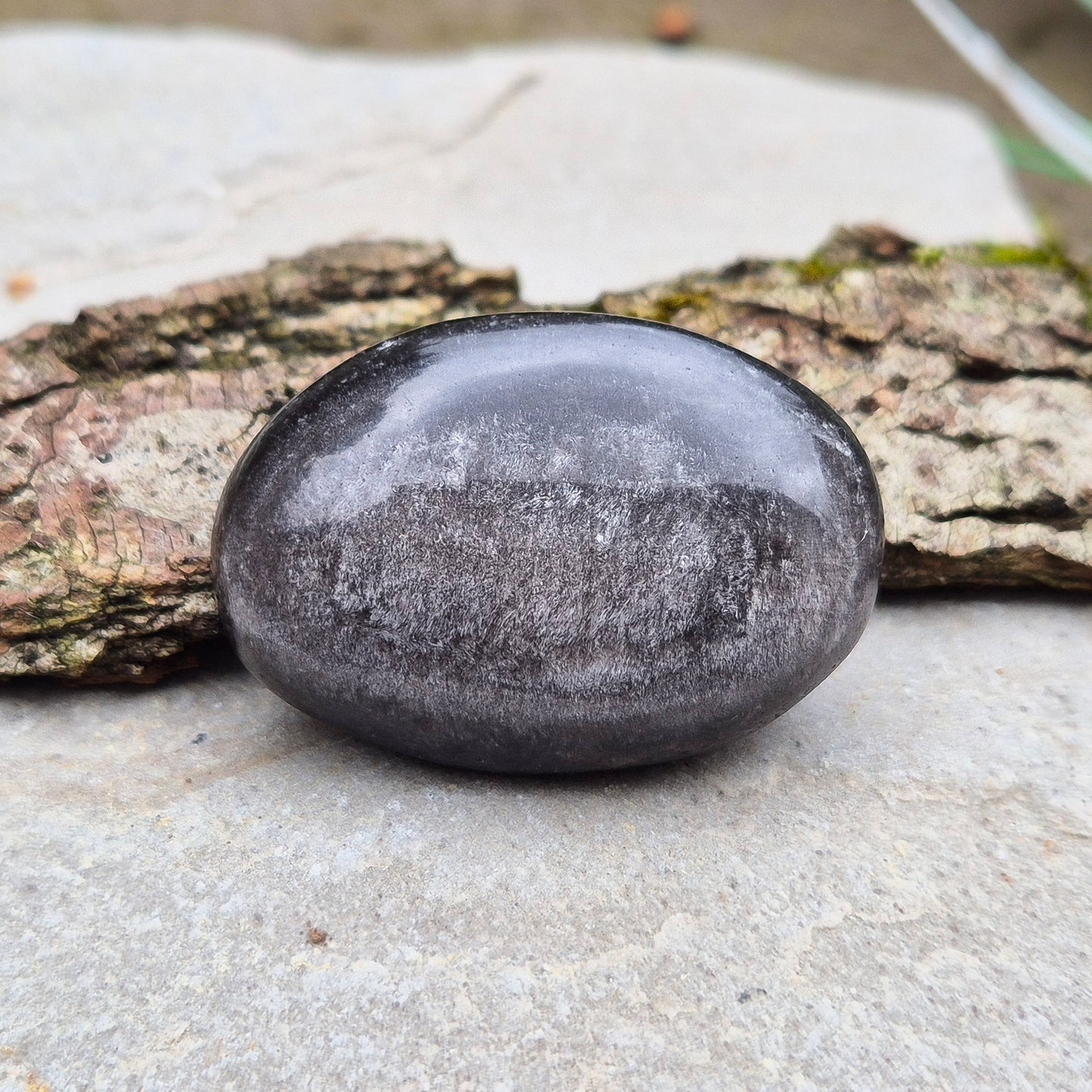 Silver Sheen Obsidian Crystal Palm Stone. Silver sheen obsidian is a type of volcanic glass which is primarily black or dark grey and has a distinctive silvery or metallic sheen on its surface