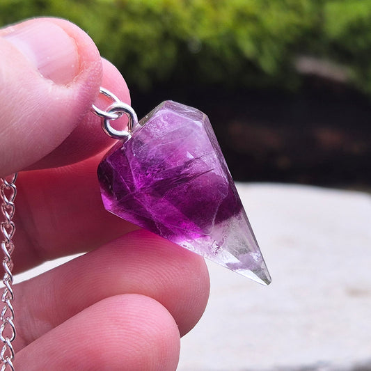 Fluorite Crystal Pendulum. Colour is purple with a clear tip, tip is rounded. 