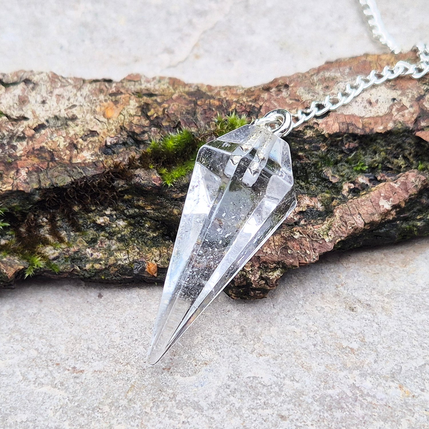 Clear Quartz Crystal Pendulum for dowsing and energy work. Comes in a box or pouch for easy storage. The chain features a silver ring for a comfortable grip.