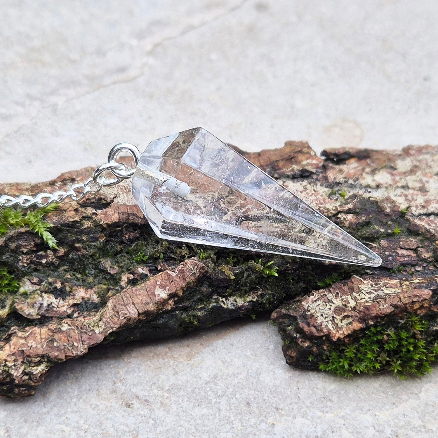 Clear Quartz Crystal Pendulum for dowsing and energy work. Comes in a box or pouch for easy storage. The chain features a silver ring for a comfortable grip.