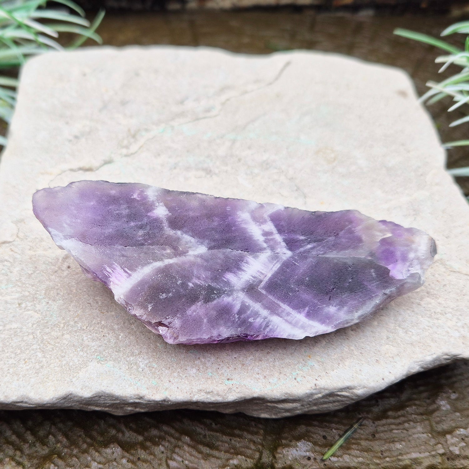 Chevron Amethyst Crystal Platform. One side is left untouched in its raw form, while the other is cut flat to create a versatile platform for displaying crystals,